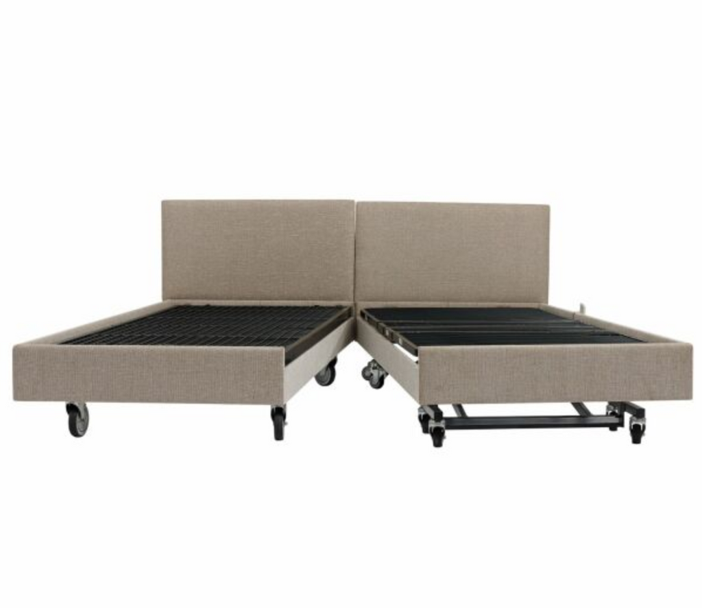 An adjustable bed frame with two separate upholstered headboard sections, shown in a light beige fabric with black metal slats and casters on a white background.