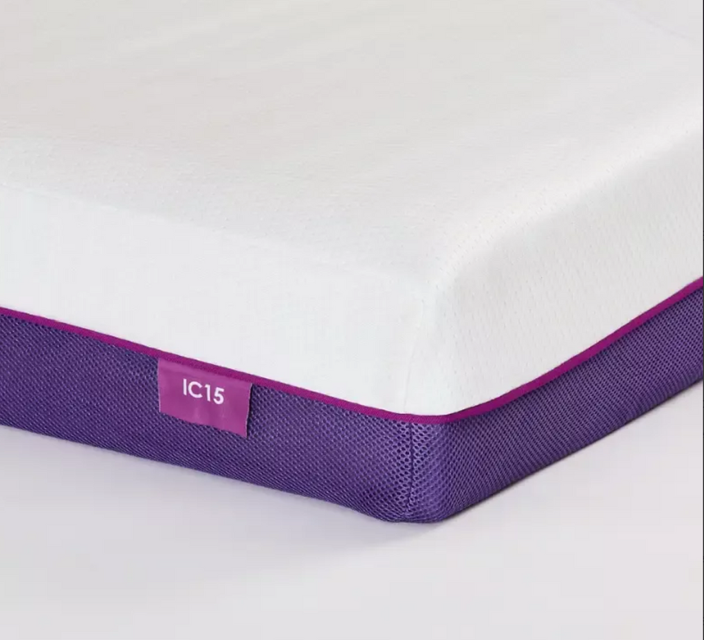 A close-up studio shot of a mattress corner showing a white top surface, a purple mesh side border, and a small purple label reading IC15.