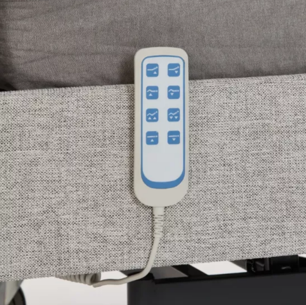 A close-up of an electric recliner armrest control remote with blue buttons on a white faceplate, attached to a gray fabric-covered armrest.